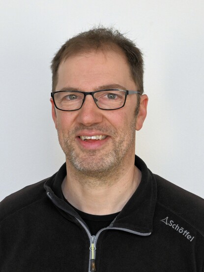 Mann der lächelt, mit dunklen kurzen Haaren und Brille